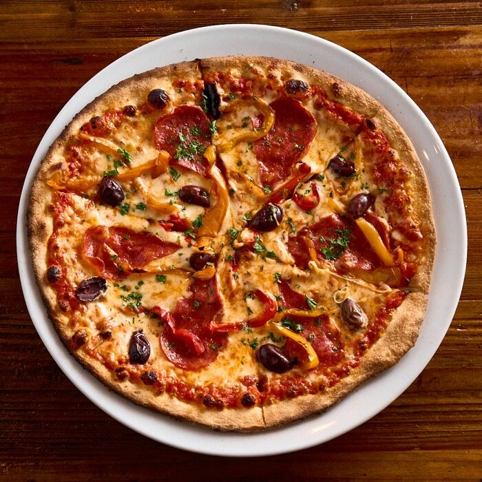 Diavola pizza with spicy salami, roasted peppers and kalamata olives on chili-garlic tomato sauce
