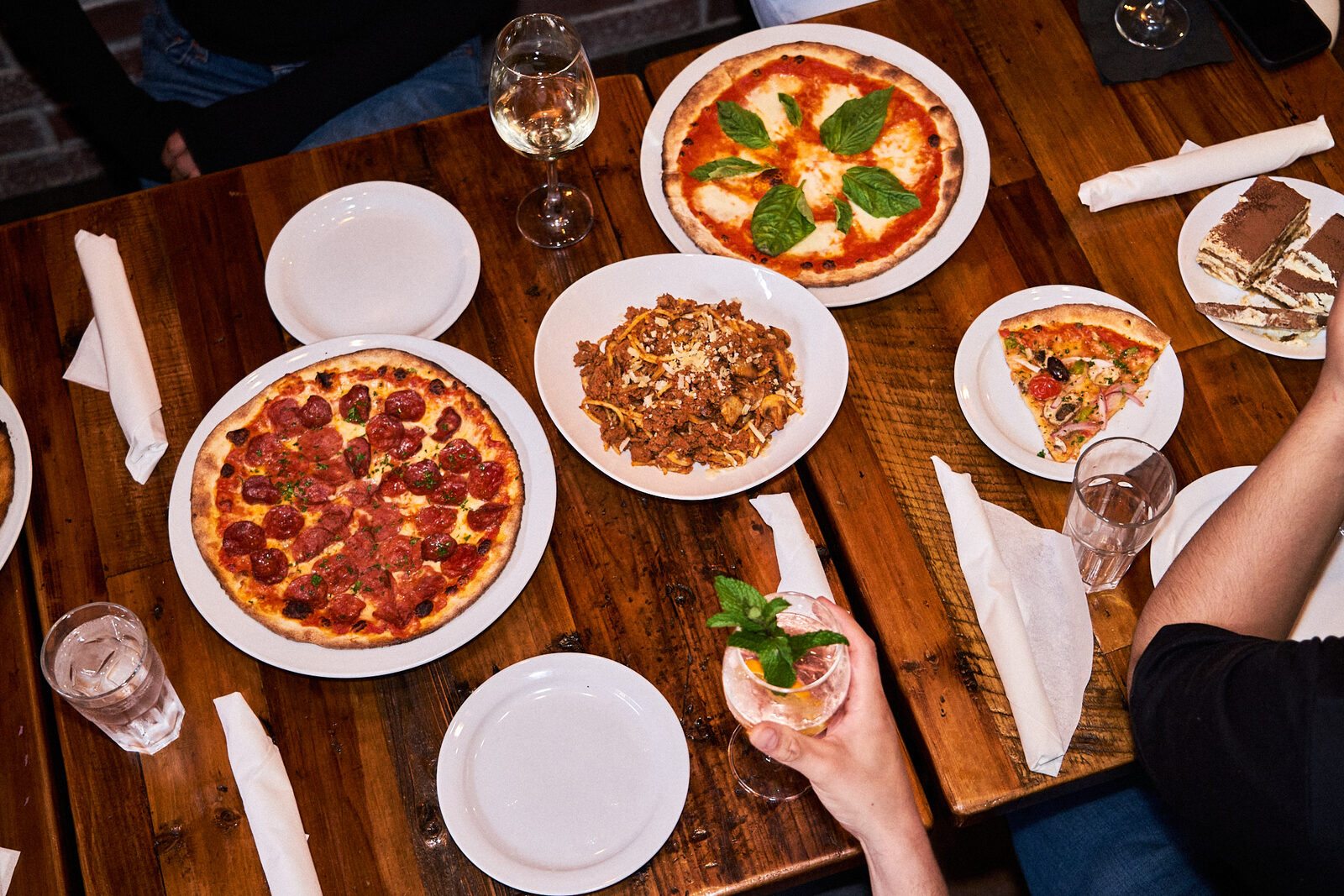 Overhead spread of pizzas, pasta and salad across a shared table at JZ's Pizza